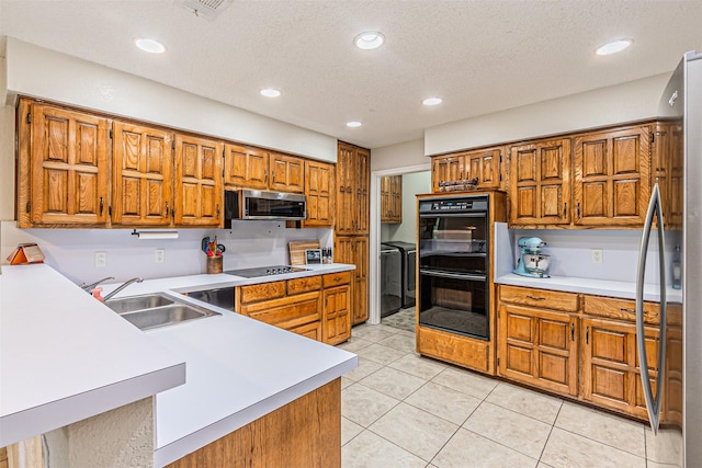 kitchen with brown cabinets, a sink, light countertops, light tile patterned floors, and black appliances