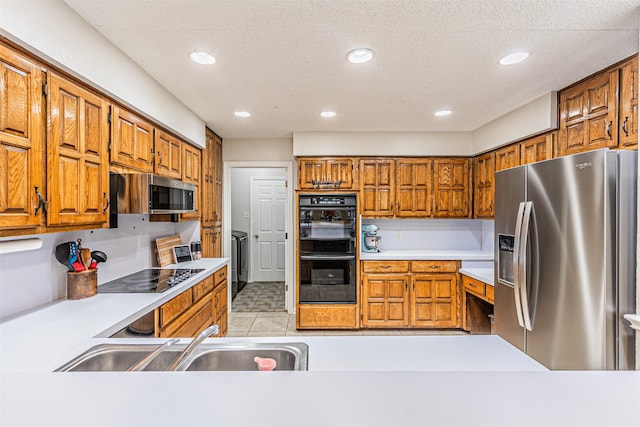 kitchen with brown cabinets, a sink, black appliances, and light countertops