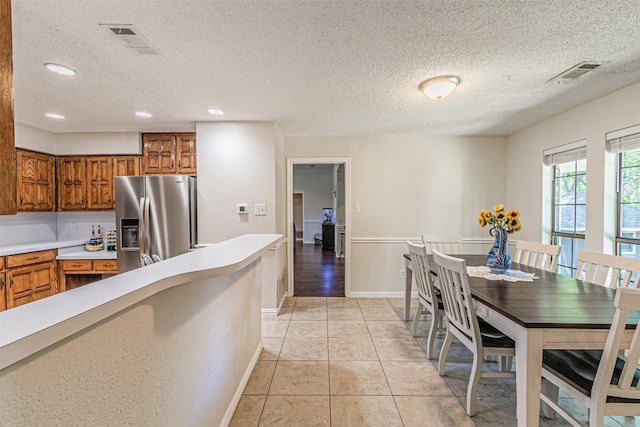 kitchen with stainless steel fridge with ice dispenser, brown cabinets, and visible vents