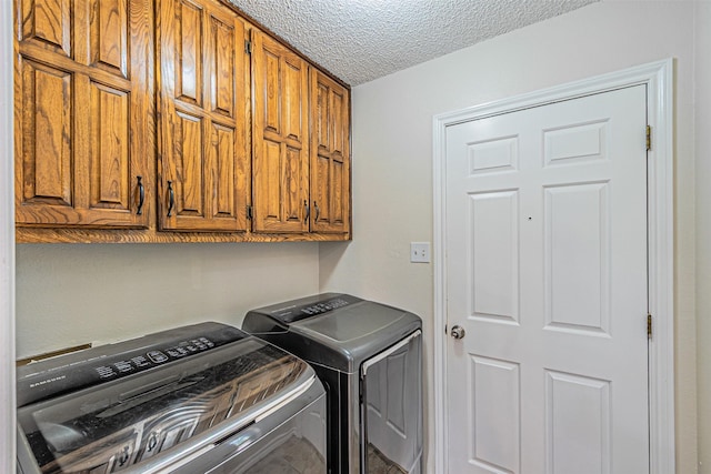 washroom with a textured ceiling, cabinet space, and washer and dryer