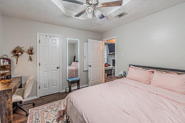 bedroom featuring a ceiling fan, dark wood-style flooring, a textured ceiling, visible vents, and baseboards