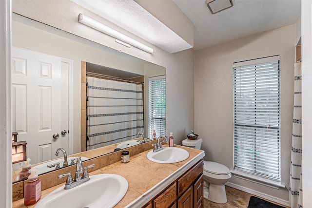 bathroom featuring toilet, a wealth of natural light, and a sink