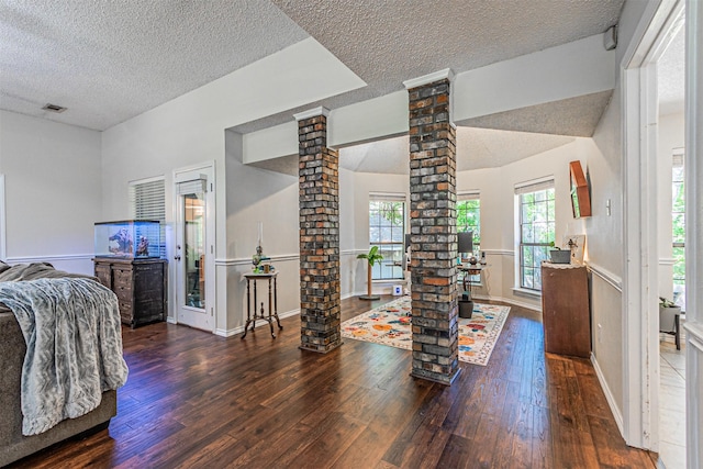 bedroom featuring decorative columns, hardwood / wood-style flooring, and a textured ceiling