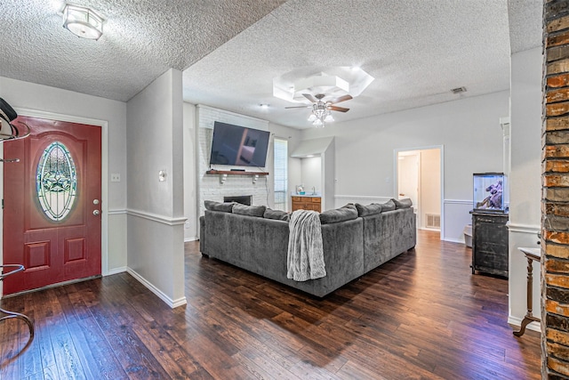 living room featuring wood-type flooring, a textured ceiling, ceiling fan, and a fireplace