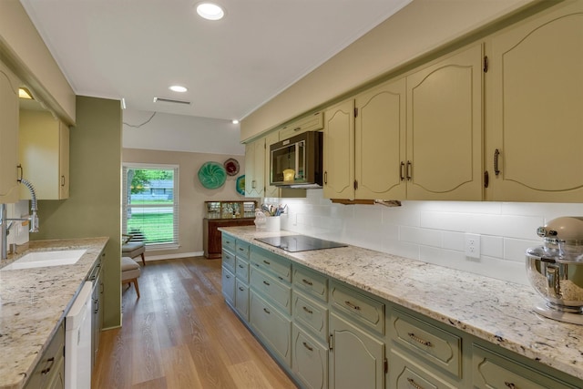 kitchen with white dishwasher, black electric stovetop, tasteful backsplash, a sink, and light wood finished floors
