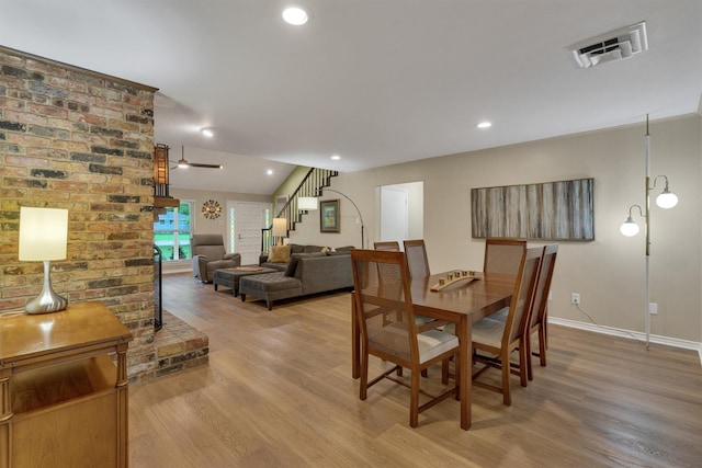 dining room featuring stairs, baseboards, visible vents, and light wood finished floors