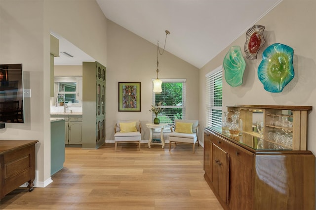 living area with baseboards, high vaulted ceiling, visible vents, and light wood-style flooring