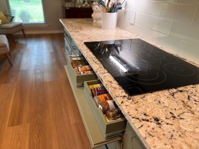 kitchen with light stone counters, black electric cooktop, and wood finished floors