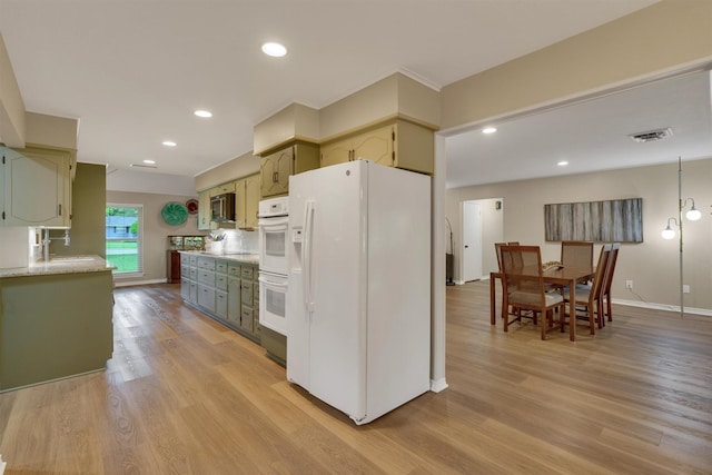 kitchen with visible vents, white appliances, light countertops, a sink, and light wood finished floors