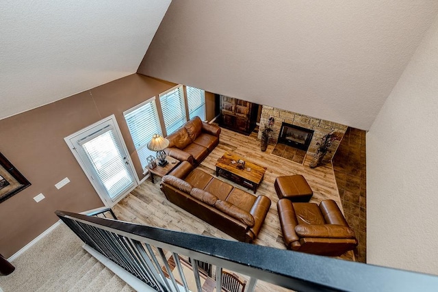 stairs featuring a stone fireplace, lofted ceiling, and baseboards