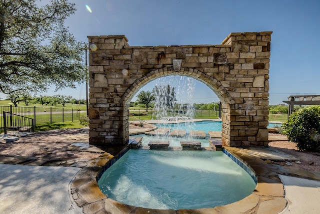 view of swimming pool with fence and a pool with connected hot tub