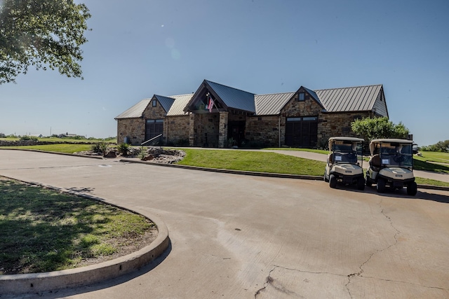 view of front of property with metal roof, a front yard, and stone siding
