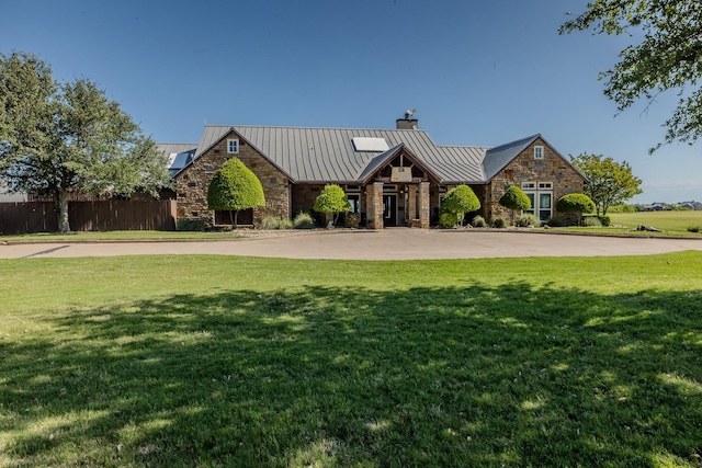 view of front facade featuring roof mounted solar panels, a standing seam roof, stone siding, and a chimney