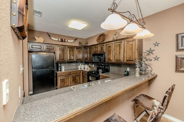 kitchen featuring black appliances, a sink, a breakfast bar area, and backsplash