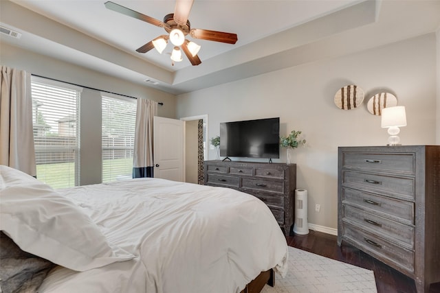 bedroom featuring baseboards, visible vents, a raised ceiling, and dark wood-type flooring