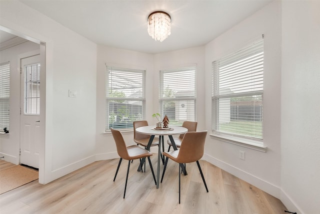 dining space with light wood-style flooring, a wealth of natural light, a chandelier, and baseboards