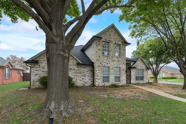 view of front of house featuring a front lawn, fence, a shingled roof, and brick siding