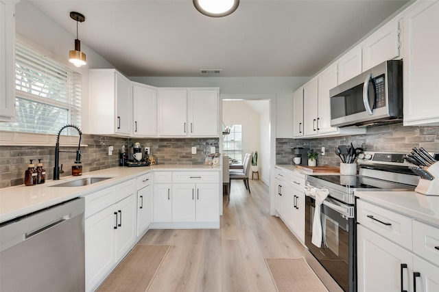 kitchen with a sink, tasteful backsplash, stainless steel appliances, and visible vents