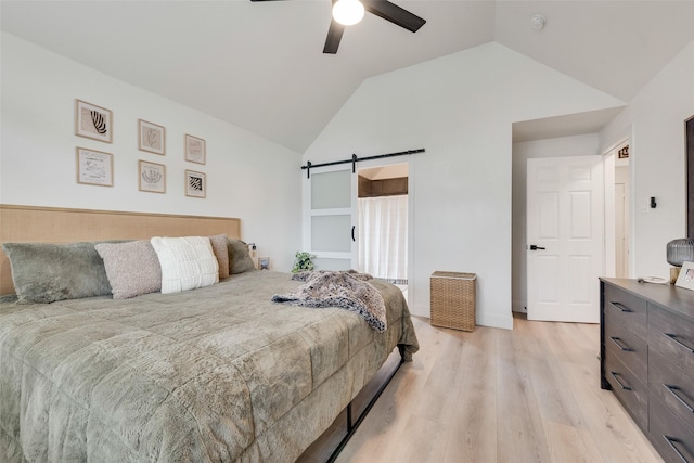 bedroom featuring lofted ceiling, ceiling fan, a barn door, and light wood-type flooring