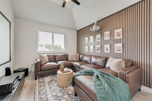 living room featuring light wood finished floors, a ceiling fan, and vaulted ceiling