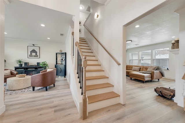 staircase with visible vents, wood finished floors, and recessed lighting