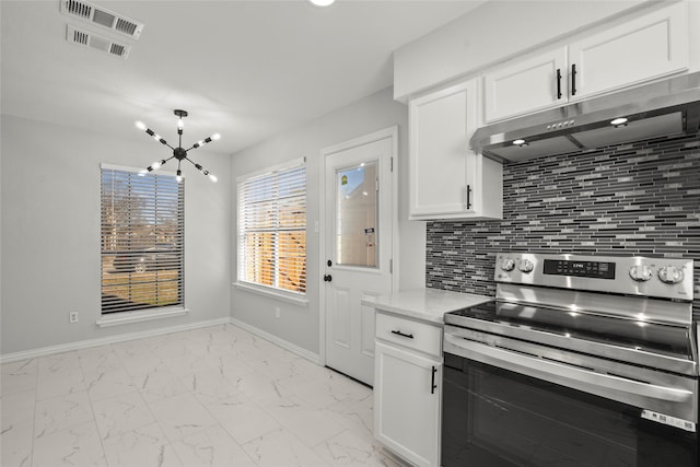 kitchen with marble finish floor, white cabinetry, under cabinet range hood, tasteful backsplash, and stainless steel range with electric cooktop