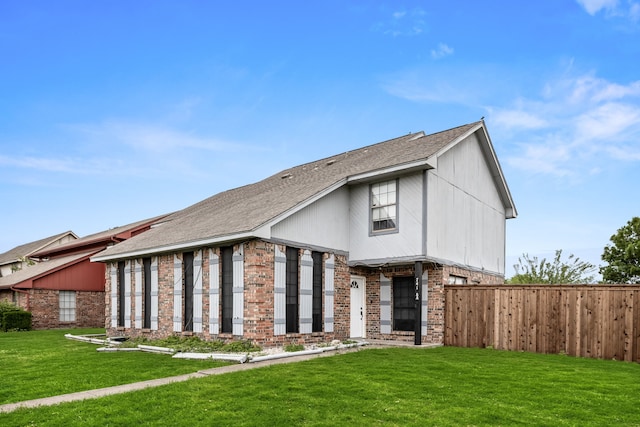 view of front of house with fence, roof with shingles, a front lawn, and brick siding
