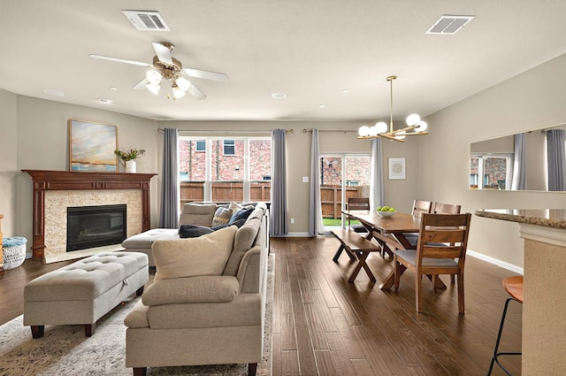 living area with baseboards, visible vents, ceiling fan with notable chandelier, and dark wood-style floors