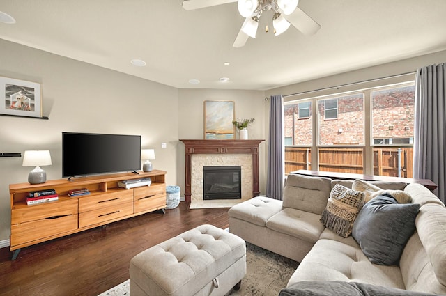 living area featuring dark wood-type flooring, ceiling fan, and a tiled fireplace