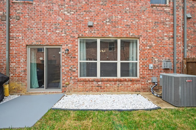 rear view of house featuring cooling unit, a patio, and brick siding