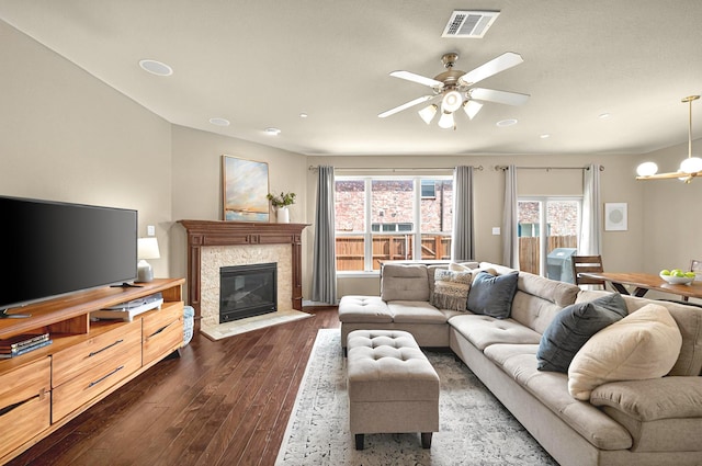 living area with dark wood-style flooring, visible vents, a wealth of natural light, and ceiling fan with notable chandelier
