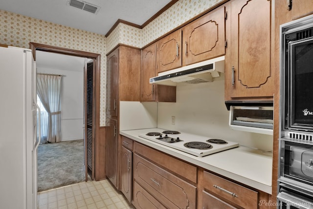 kitchen with under cabinet range hood, white appliances, visible vents, light countertops, and wallpapered walls