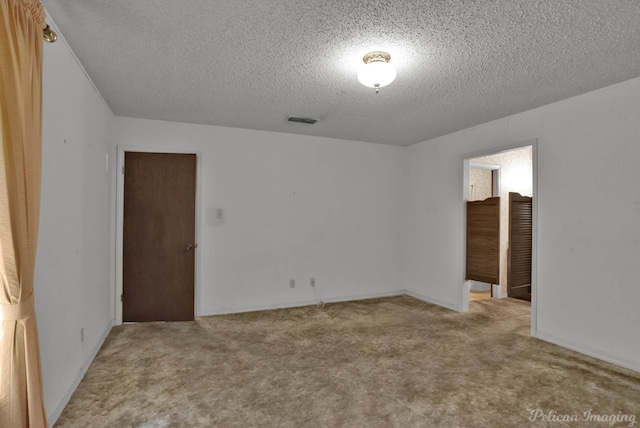 unfurnished room featuring a textured ceiling, visible vents, and carpet flooring