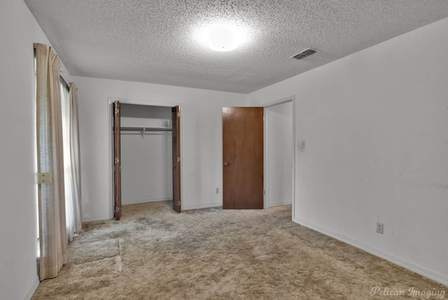 unfurnished bedroom featuring a textured ceiling, carpet flooring, visible vents, baseboards, and a closet