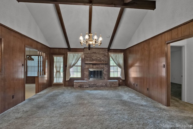 unfurnished living room featuring beamed ceiling, carpet flooring, wood walls, and a chandelier
