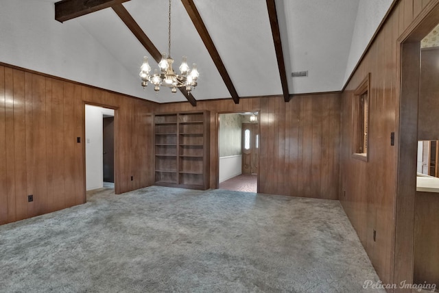 unfurnished room with visible vents, carpet floors, beam ceiling, wooden walls, and a notable chandelier