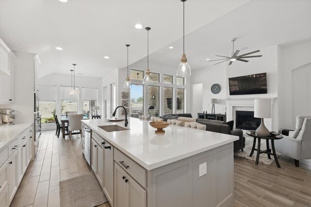 kitchen with a sink, light wood-style floors, white cabinetry, light countertops, and appliances with stainless steel finishes