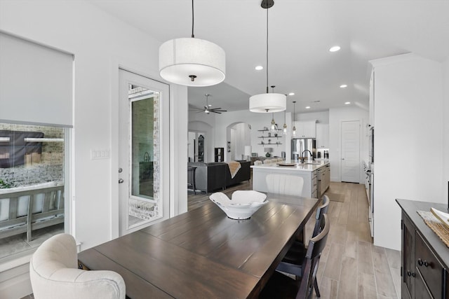 dining room featuring light wood-style floors, ceiling fan, recessed lighting, and arched walkways