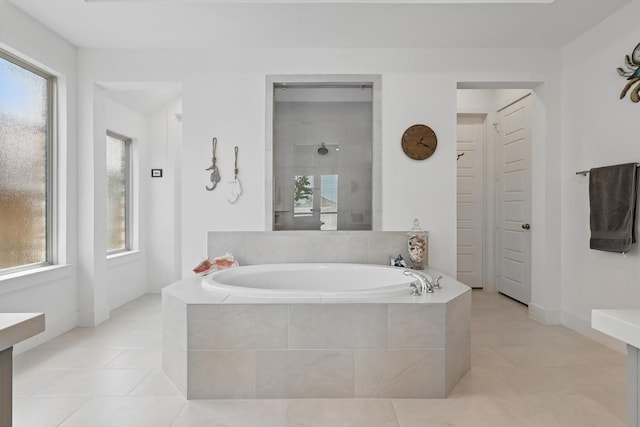 bathroom with baseboards, a tile shower, a garden tub, and tile patterned flooring