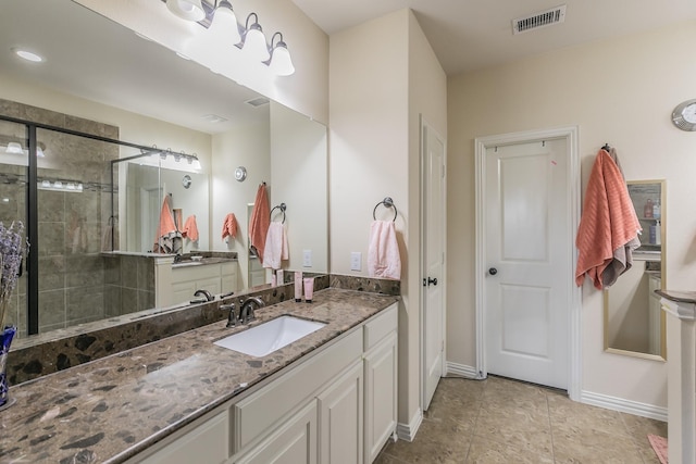 bathroom with visible vents, tiled shower, vanity, and baseboards