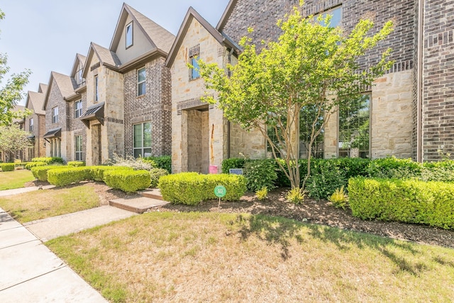 view of front of property with brick siding, a front yard, and stone siding