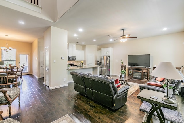 living room featuring baseboards, recessed lighting, ceiling fan with notable chandelier, and dark wood-type flooring