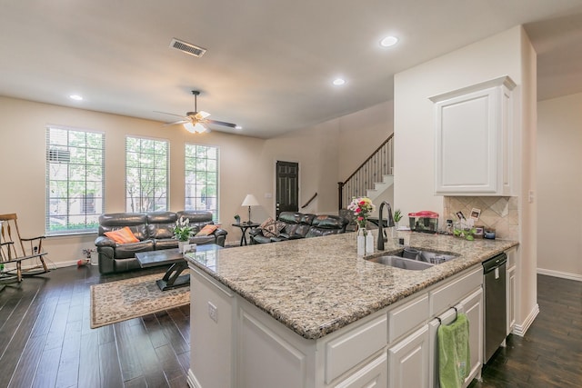 kitchen featuring light stone countertops, a sink, visible vents, stainless steel dishwasher, and dark wood finished floors