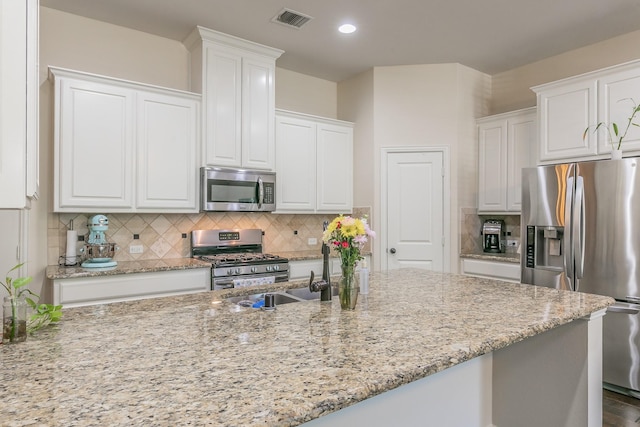 kitchen with white cabinets, a sink, appliances with stainless steel finishes, visible vents, and backsplash