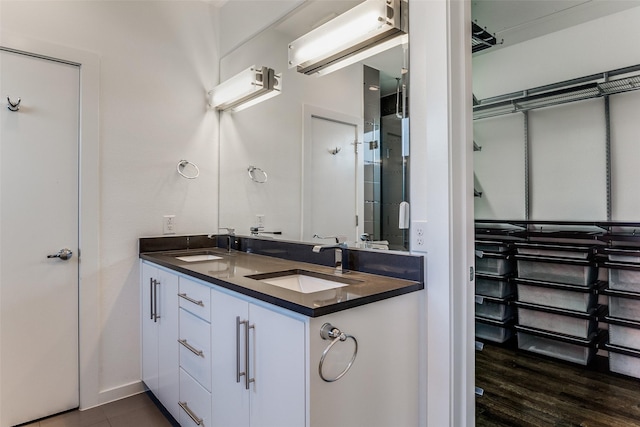 full bath with double vanity, a sink, wood finished floors, and baseboards