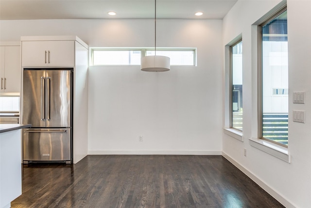 unfurnished dining area featuring dark wood-style floors, recessed lighting, a healthy amount of sunlight, and baseboards