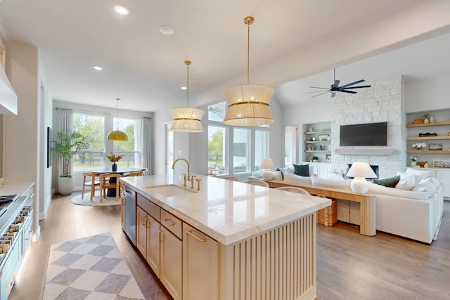 kitchen with ceiling fan, recessed lighting, light stone counters, a sink, and light wood finished floors