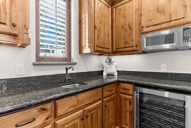 kitchen with stainless steel microwave, a sink, brown cabinets, and beverage cooler