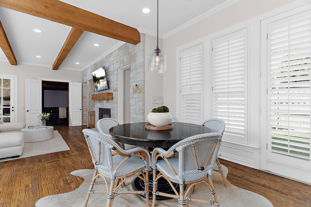 dining space with beam ceiling, recessed lighting, ornamental molding, wood finished floors, and a stone fireplace