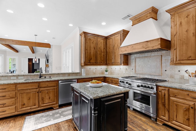 kitchen featuring light stone counters, a sink, appliances with stainless steel finishes, premium range hood, and dark wood-style floors